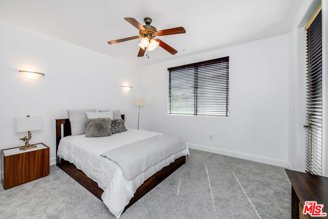 4724 Kester Avenue, Unit 209 Sherman Oaks, CA 91403 - Photo 21 of 27 a bedroom with a large bed and a chandelier