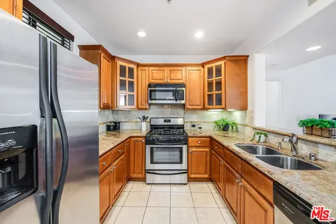 a kitchen with stainless steel appliances granite countertop a refrigerator a stove and a sink