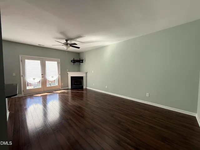 an empty room with wooden floor fireplace and windows