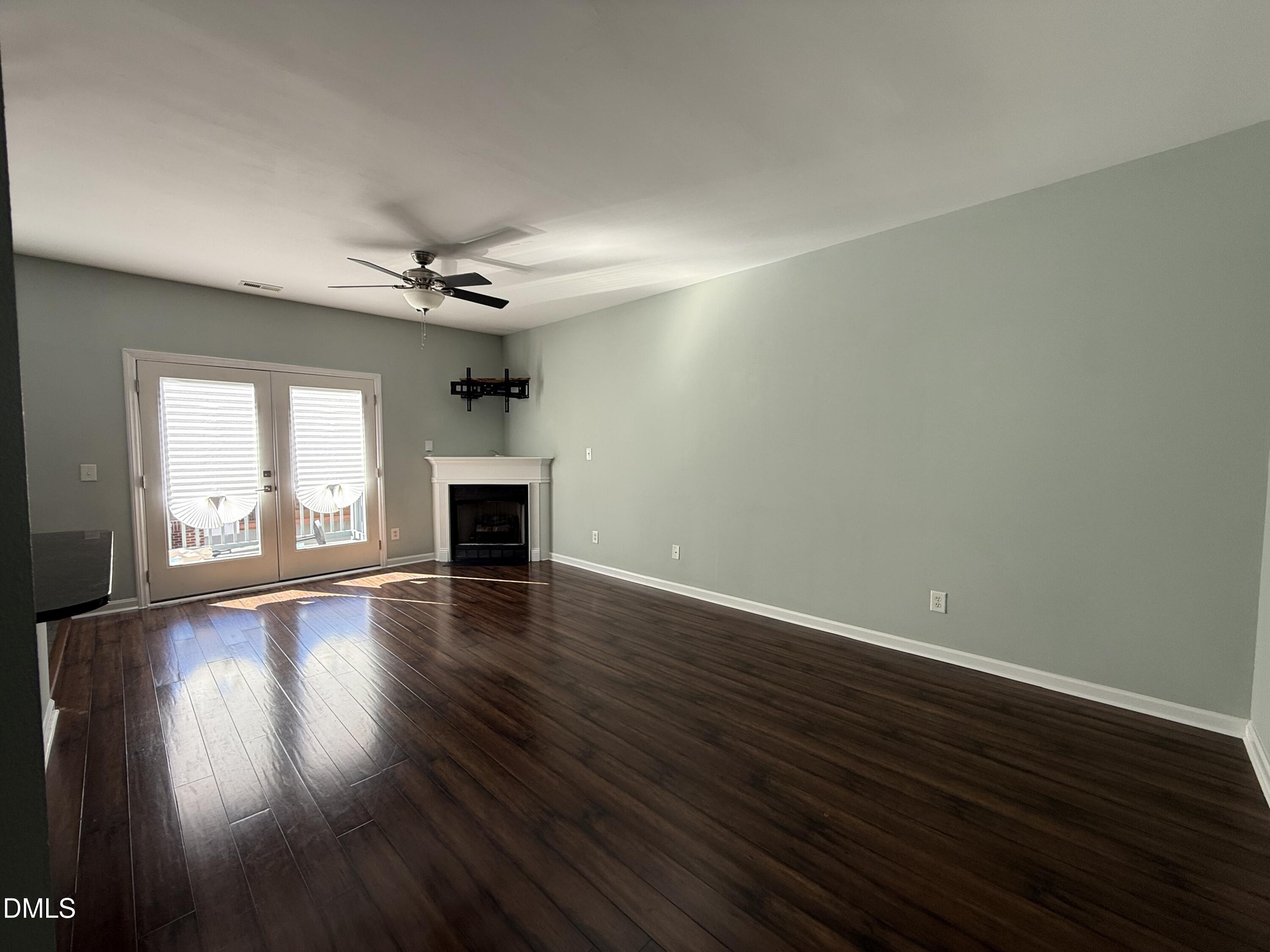 606 Sawcut Lane Apex, NC 27502 - Photo 4 of 30 an empty room with wooden floor fireplace and windows