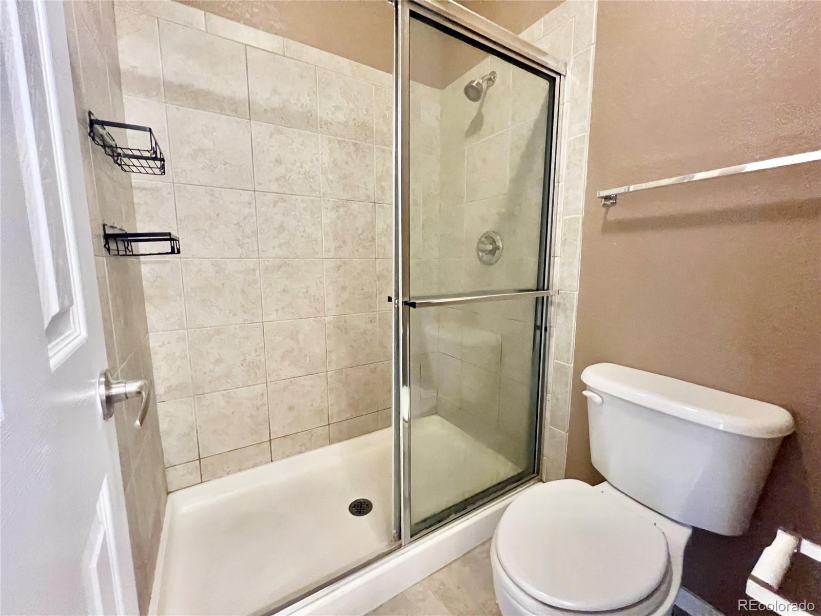 1385 South Chambers Road, Unit 102 Aurora, CO 80017 - Photo 13 of 20 a white toilet sitting next to a bath tub and a shower