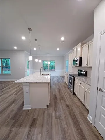 a kitchen with stainless steel appliances kitchen island granite countertop wooden floors wooden cabinets and sink