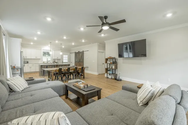 a living room with furniture ceiling fan and a flat screen tv