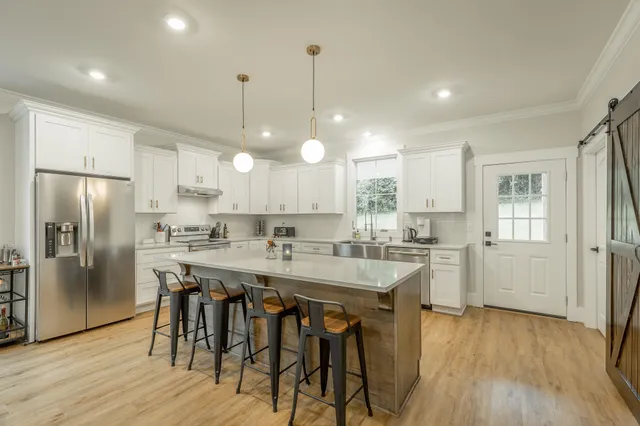 a kitchen with stainless steel appliances granite countertop a dining table chairs refrigerator and microwave