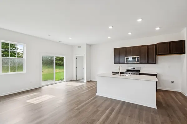a kitchen with stainless steel appliances a microwave a stove a sink a refrigerator cabinets and a window