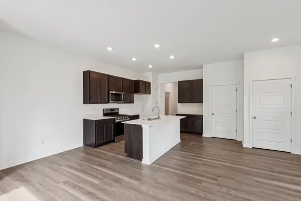 a large white kitchen with stainless steel appliances kitchen island granite countertop a stove top oven a sink and dishwasher with wooden floor