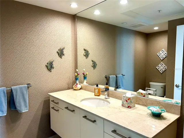 a bathroom with a granite countertop sink a toilet and mirror