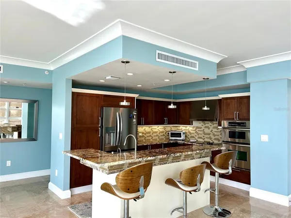 a kitchen with stainless steel appliances kitchen island granite countertop a stove and a refrigerator