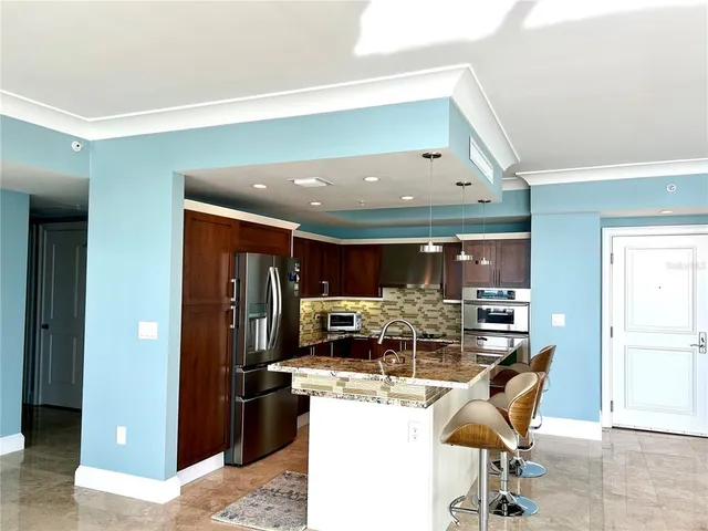 a kitchen with stainless steel appliances kitchen island granite countertop a refrigerator and a stove top oven