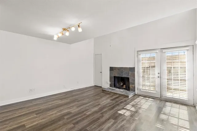 a view of an empty room with wooden floor fireplace and a window