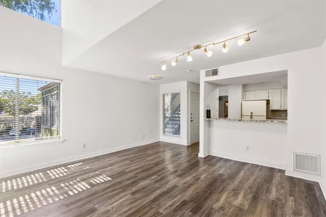 a view of a hallway with wooden floor and a living room
