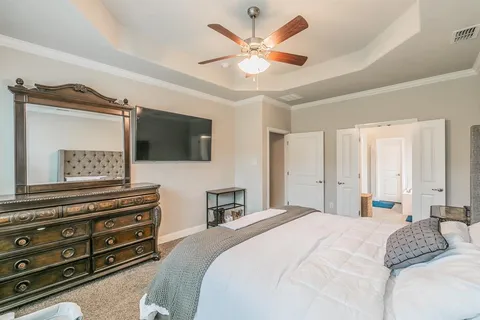 a bedroom with a bed a dresser and a flat screen tv