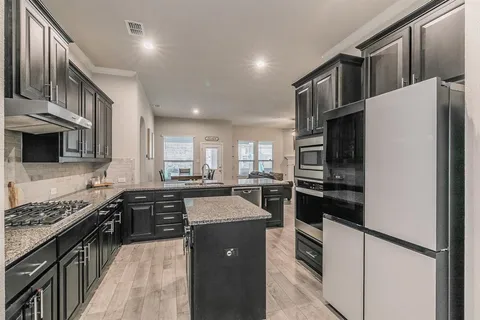 a kitchen with stainless steel appliances granite countertop a refrigerator a stove a sink and a microwave