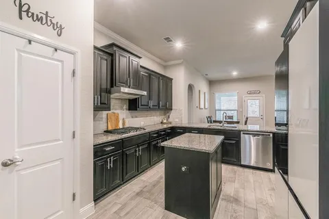 a kitchen with stainless steel appliances granite countertop a stove top oven a sink dishwasher a refrigerator and a cabinets