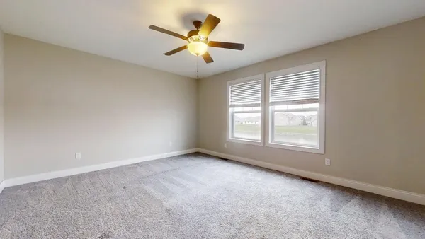 a view of an empty room with chandelier fan and a window