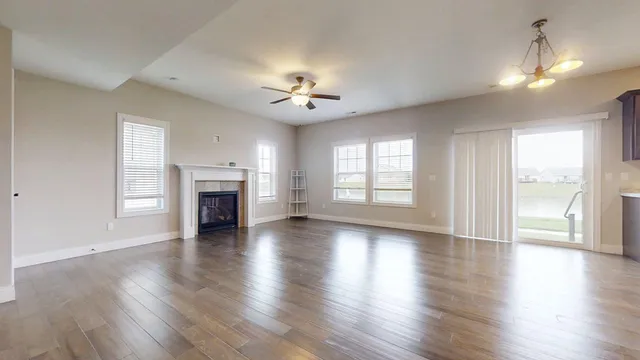 an empty room with wooden floor fireplace and windows