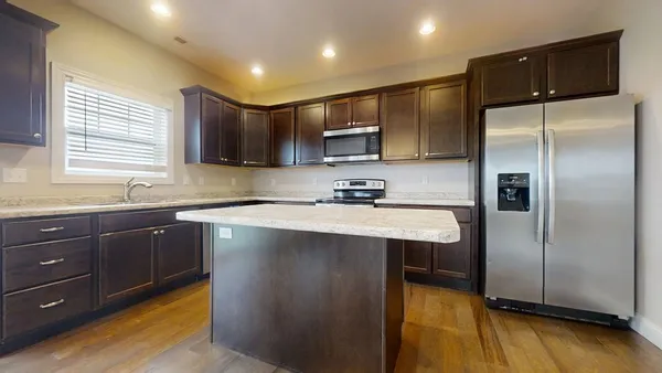 a kitchen with stainless steel appliances granite countertop a refrigerator a sink dishwasher a stove and a microwave oven on the blue painted walls