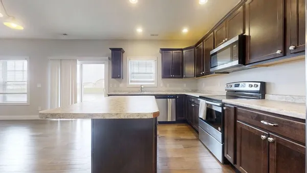 a large kitchen with stainless steel appliances granite countertop a stove a sink and a microwave