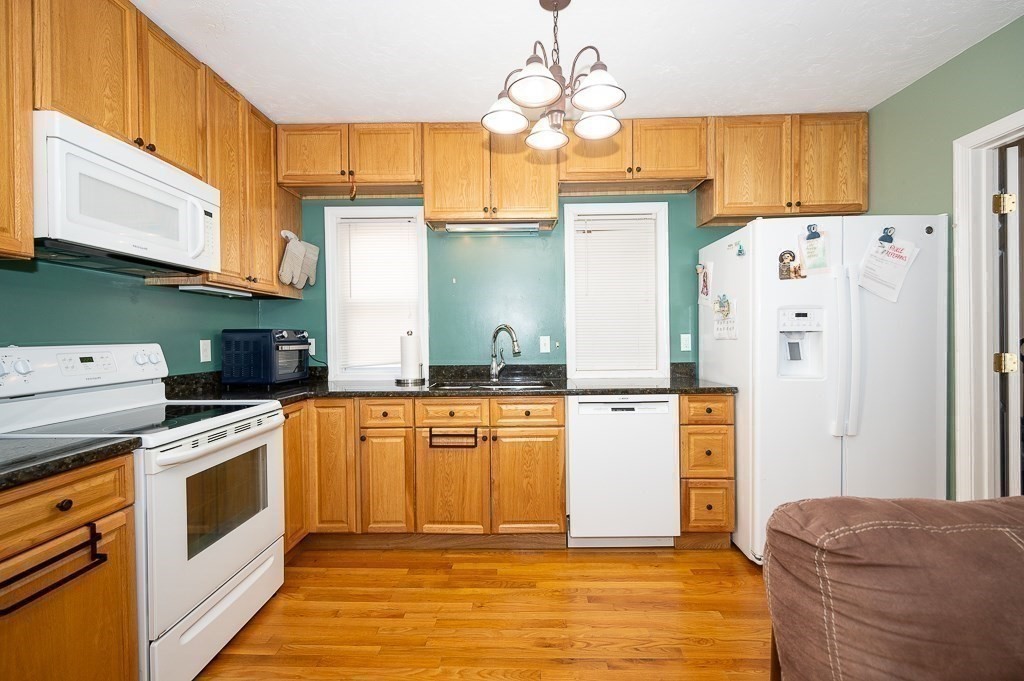 134 Baker Street Gardner, MA 01440 - Photo 26 of 42 a kitchen with stainless steel appliances granite countertop a refrigerator a stove and white cabinets with wooden floors