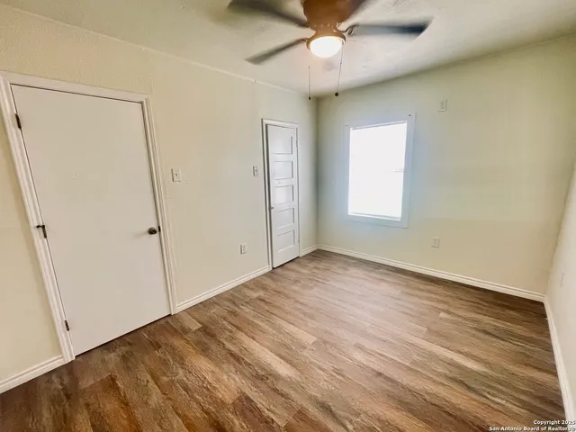 an empty room with wooden floor closet and windows