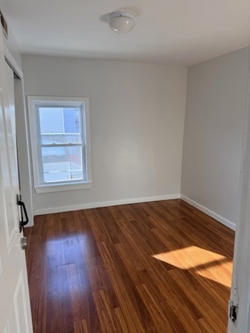 2 West 10th Street, Unit 2 Lowell, MA 01850 - Photo 6 of 13 an empty room with wooden floor and windows