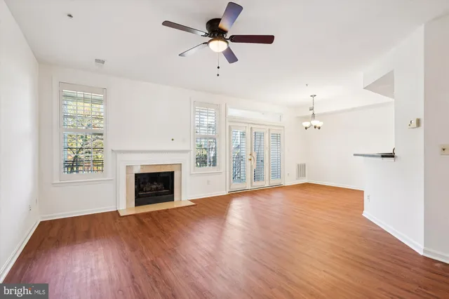 a view of empty room with wooden floor fireplace and a window