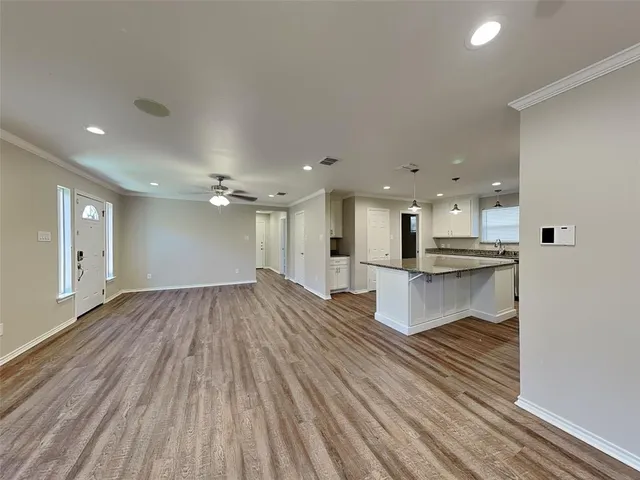a open kitchen with white cabinets and wooden floor