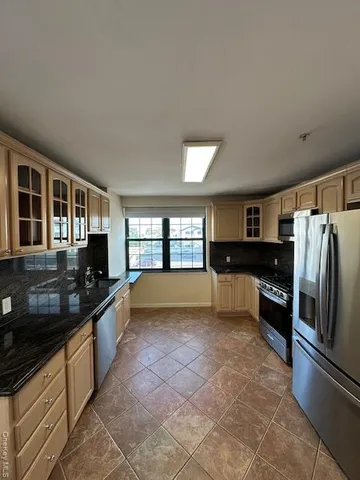a kitchen with granite countertop a refrigerator and a stove top oven