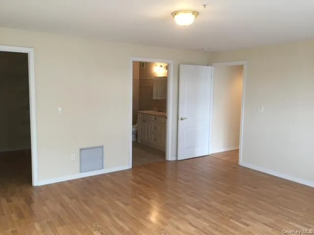 a view of an empty room with wooden floor and closet