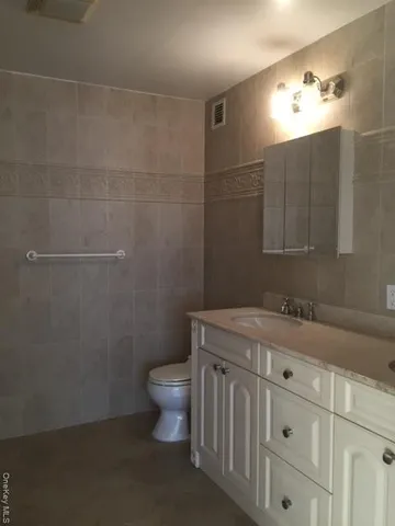 a bathroom with a granite countertop sink a toilet and a mirror