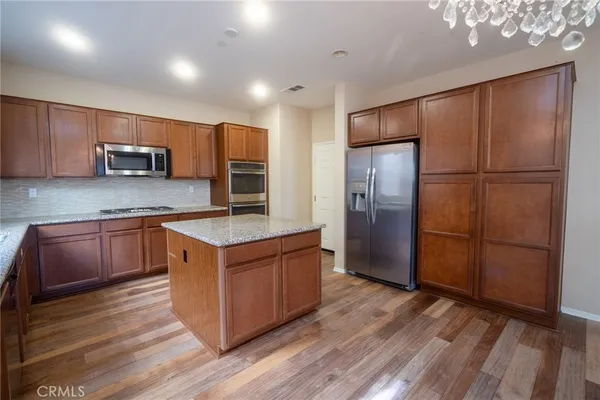 a kitchen with stainless steel appliances granite countertop a refrigerator a sink and a stove