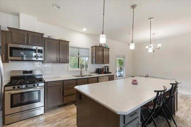 a kitchen with a stove a sink a microwave a refrigerator and chairs