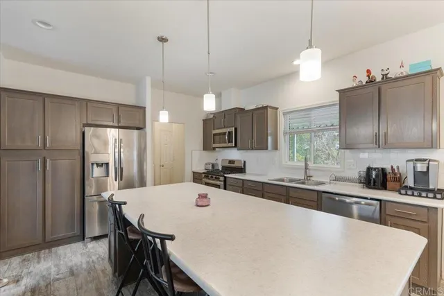 a kitchen with stainless steel appliances a sink a stove a refrigerator a center island and cabinets