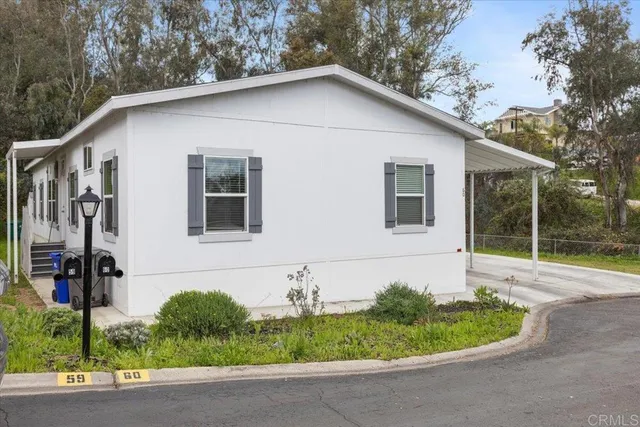 a white house with a small yard plants and big yard