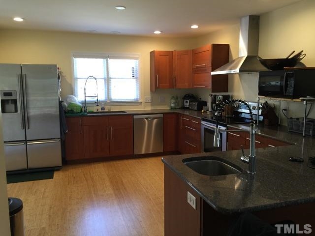 a kitchen with stainless steel appliances granite countertop a sink a stove and a refrigerator