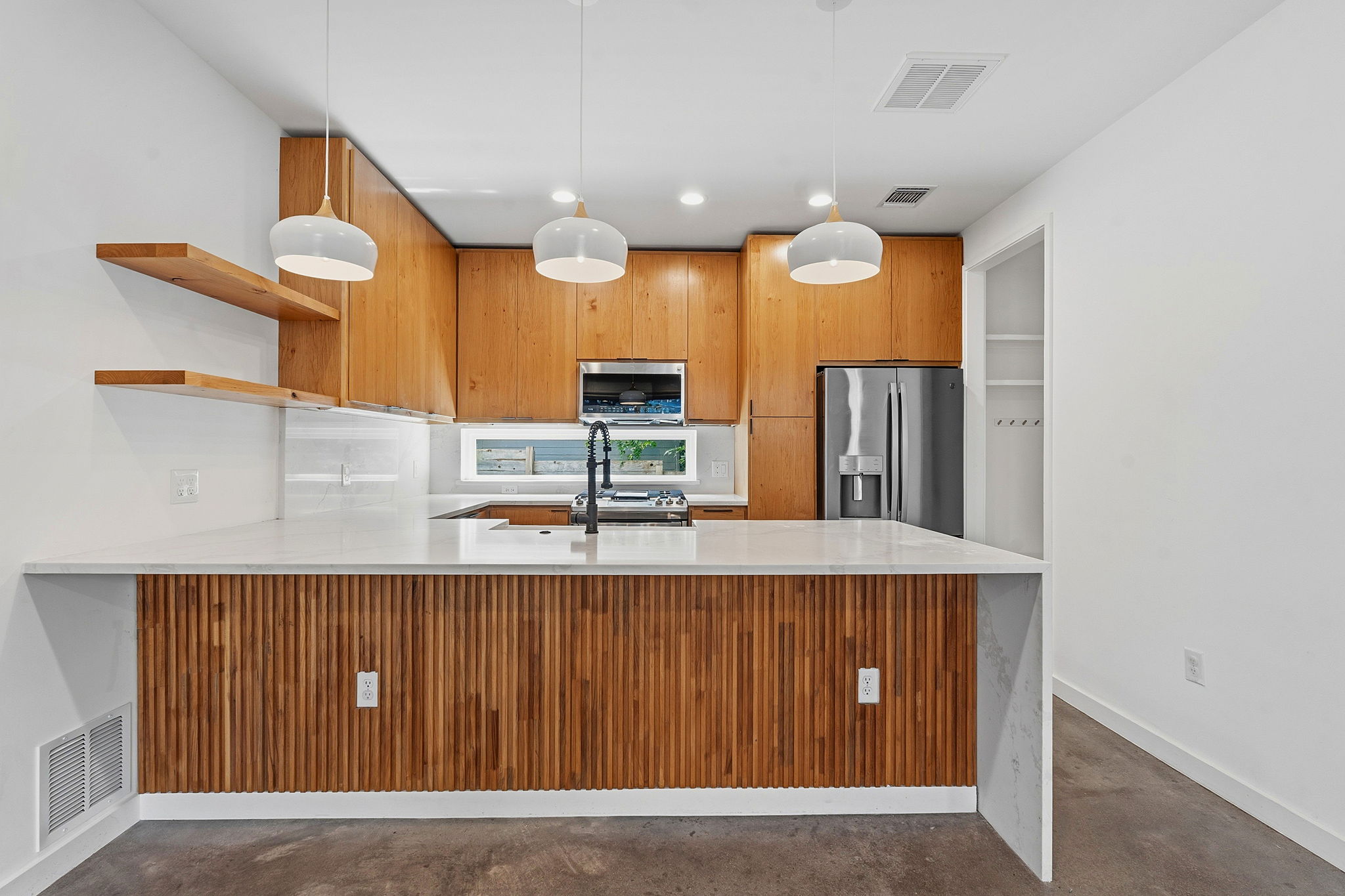 1707 Deloney Street, Unit 2 Austin, TX 78721 - Photo 7 of 26 Natural wood cabinetry and shelving complement a generous island, defining this contemporary culinary space.