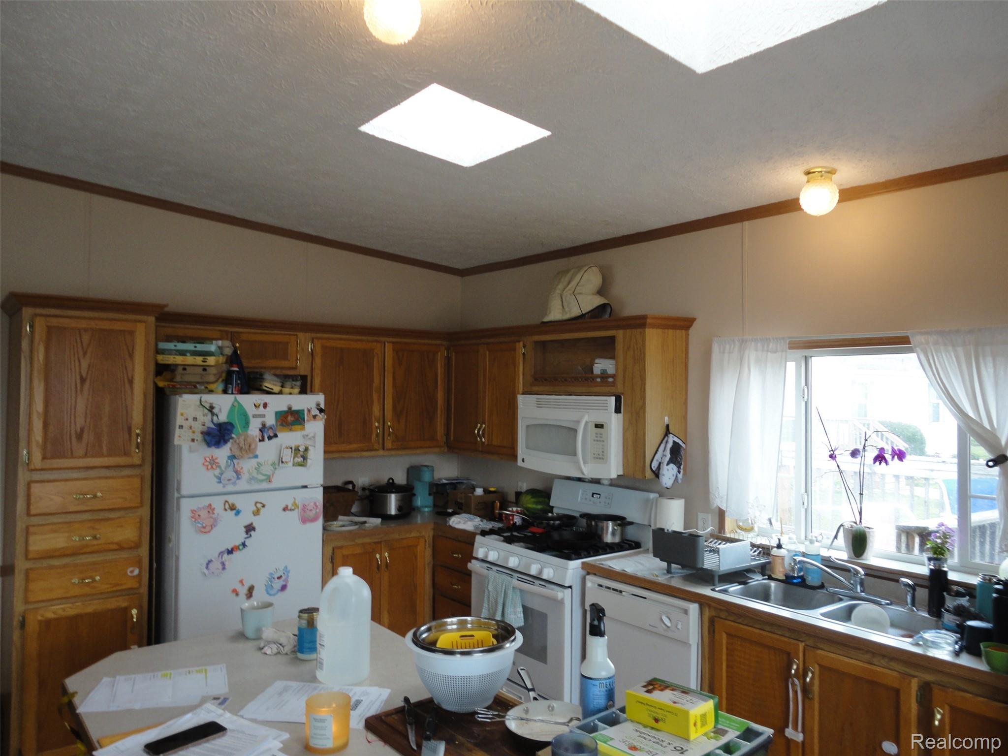 5931 Megans Ridge Monroe, MI 48161 - Photo 7 of 13 Kitchen featuring wood-finish cabinetry, built-in microwave, double-basin sink, and a window overlooking exterior space