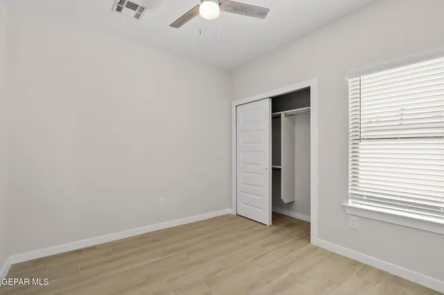 an empty room with an entryway and chandelier fan