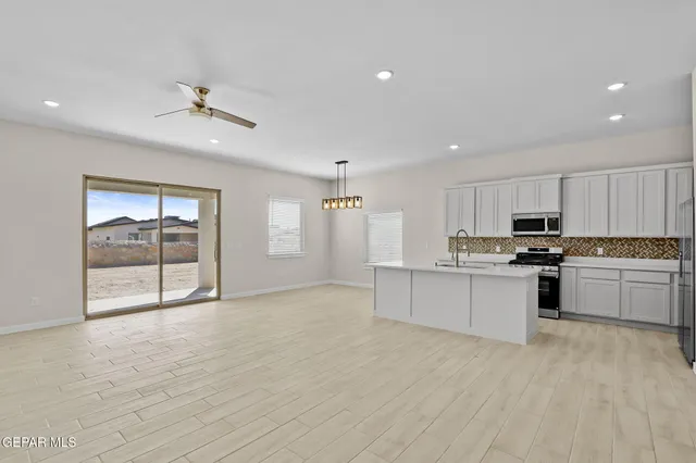 a large white kitchen with kitchen island a sink stainless steel appliances and cabinets