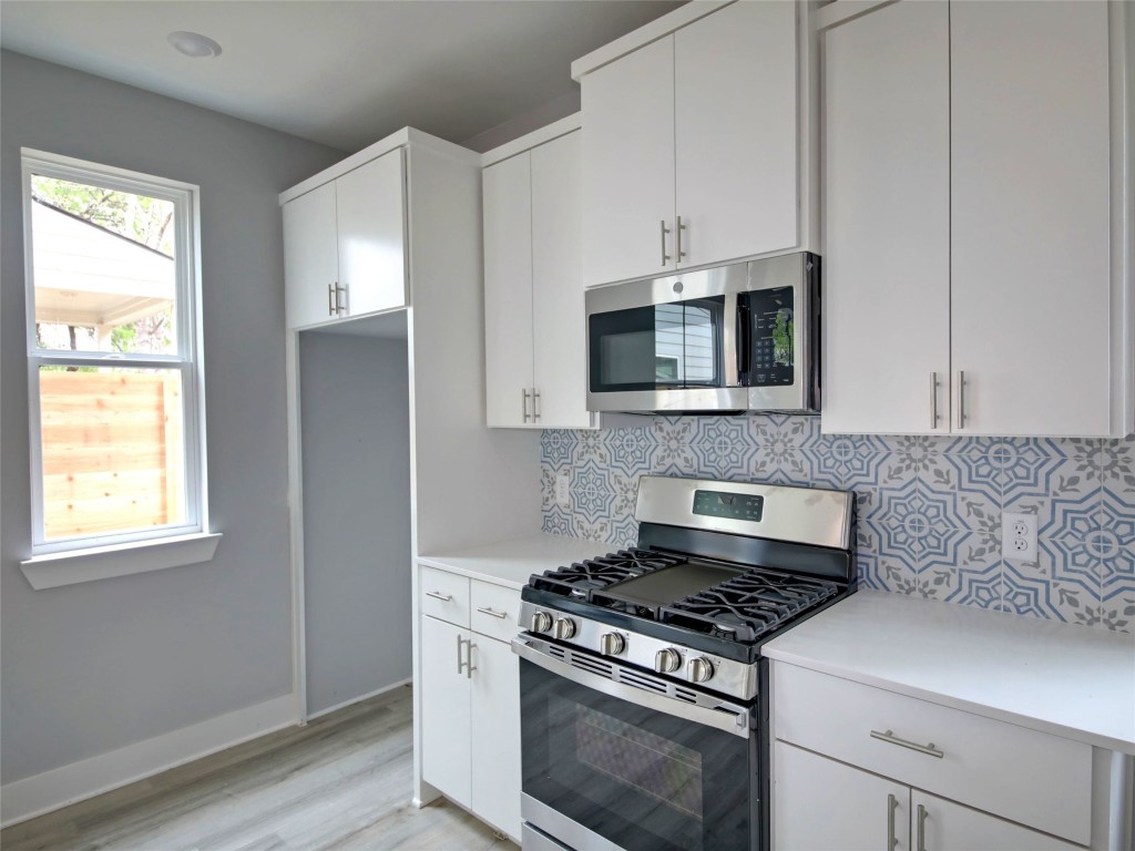 6111 Carnation Terrace, Unit 2 Austin, TX 78741 - Photo 12 of 34 Kitchen with appliances with stainless steel finishes, white cabinets, tasteful backsplash, and light wood-type flooring