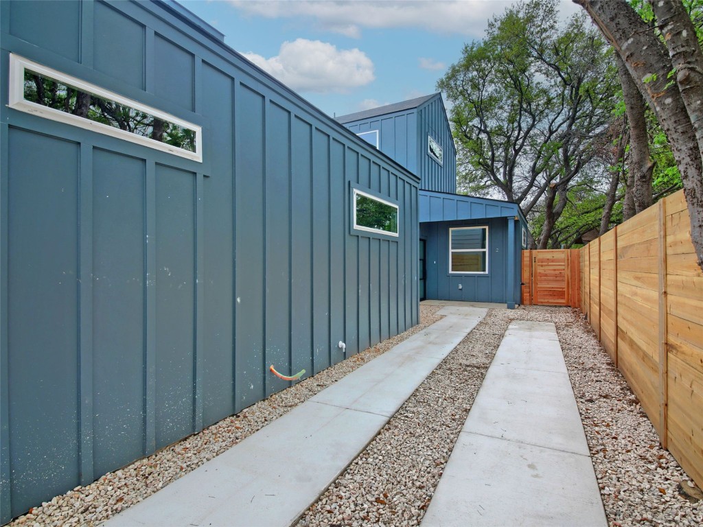 6111 Carnation Terrace, Unit 2 Austin, TX 78741 - Photo 2 of 34 View of side of property with board and batten siding and a fenced backyard