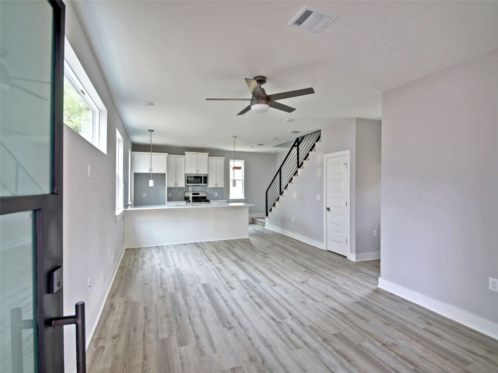 6111 Carnation Terrace, Unit 2 Austin, TX 78741 - Photo 3 of 34 Unfurnished living room featuring stairs, light wood finished floors, and ceiling fan