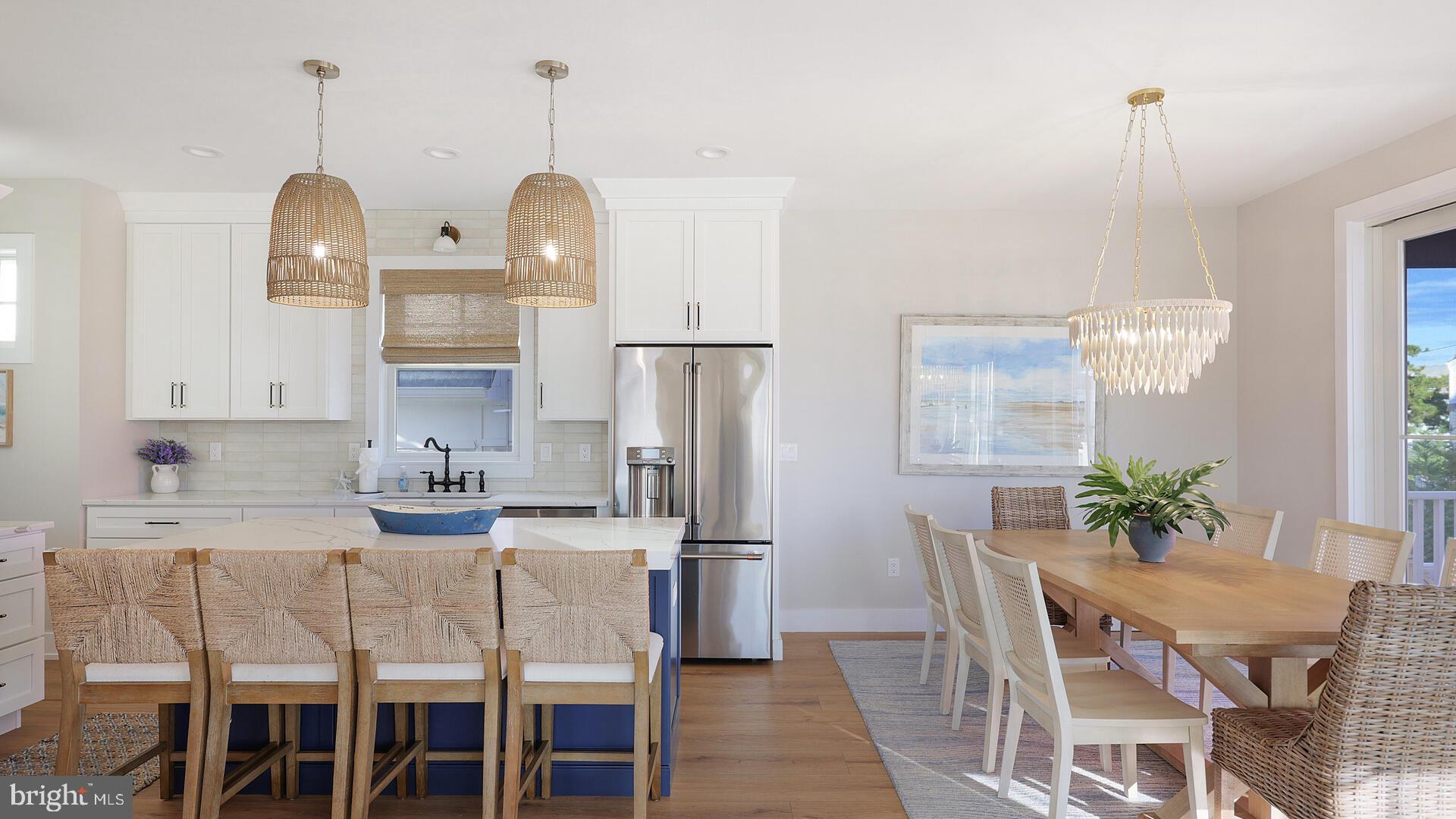 a kitchen with stainless steel appliances kitchen island granite countertop a dining table chairs and a refrigerator
