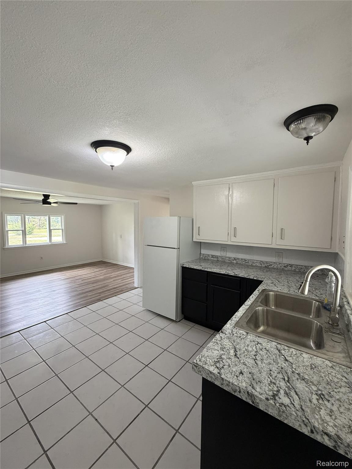 6381 Monroe Road Tipton, MI 49287 - Photo 1 of 7 Kitchen with white upper cabinetry and dark lower cabinetry, stainless steel double-basin sink, and a refrigerator