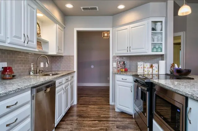 a kitchen with stainless steel appliances granite countertop a sink stove and cabinets
