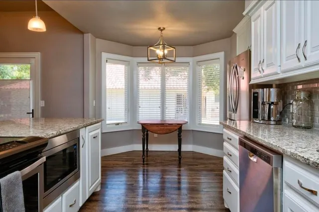 a kitchen with stainless steel appliances granite countertop a stove and a wooden floors