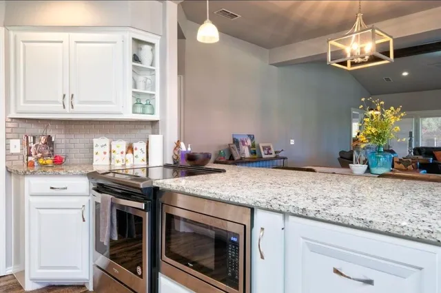 a kitchen with stainless steel appliances granite countertop a sink a stove and cabinets