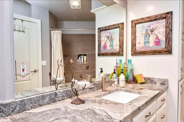 a bathroom with a granite countertop sink and a mirror