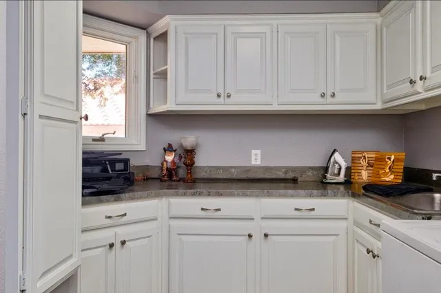 a kitchen with stainless steel appliances granite countertop white cabinets and a sink