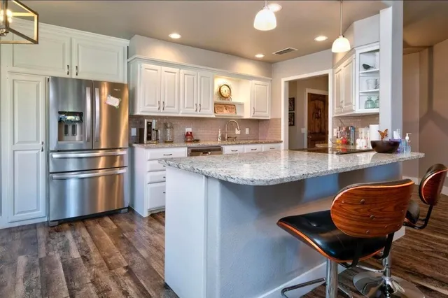 a kitchen with stainless steel appliances granite countertop a sink and a refrigerator